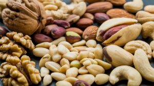 A close-up of assorted healthy nuts, including walnuts, almonds, cashews, pistachios, and peanuts, arranged together on a dark surface.